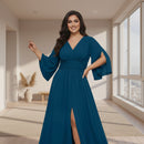 A woman modeling a floor-length teal blue gown with a V-neckline, flared bell sleeves, a fitted waist, and a high front slit, shown against a plain white background.