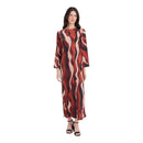A woman modeling a long-sleeved maxi dress with an abstract wavy pattern in rust red, black, and beige, paired with black strappy heels, against a plain white background.