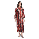 A woman modeling a long-sleeved maxi dress with an abstract wavy vertical pattern in red, black, and beige, paired with black high-heeled sandals against a plain white background.