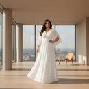 A woman modeling a white floor-length gown with a V-neckline, draped cap sleeves, a fitted waist, and a high front slit, shown against a plain white studio background.