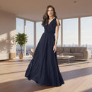 A woman modeling a floor-length navy blue gown with ruffled shoulder details, a V-neckline, and a flowing skirt against a plain white background.