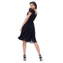 A woman modeling a short-sleeve black midi dress with a sheer tulle hem, shown from the back against a solid white background.