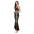 A woman modeling a floor-length black lace evening gown with a metallic gold floral pattern, set against a plain white background.